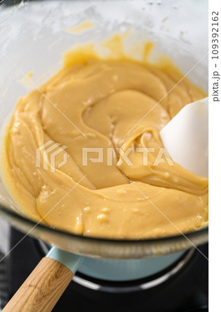 Melting white chocolate chips and other ingredients in a glass mixing bowl over boiling water to prepare cranberry pistachio fudge. Melting white chocolate chips and other ingredients in a glass mixing bowl over boiling water to prepare cranberry pistachio fudge. 109392162