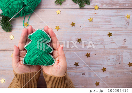 Knitted Christmas tree in woman hands. Close-up. Handmade Christmas gifts 109392413