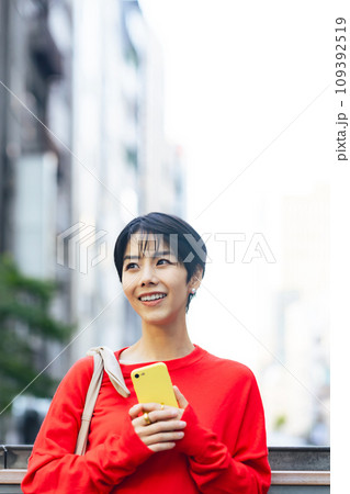 スマホを持って街を歩く女性 109392519