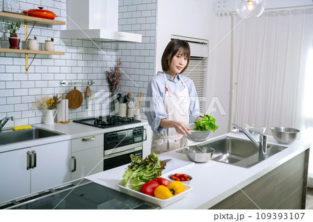 キッチンでサラダを作る女性 109393107