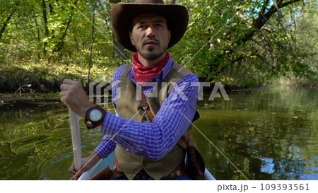 Cowboy in a canoe floats on the river in the forest 109393561