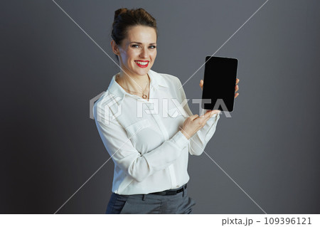 smiling business owner woman showing tablet PC isolated on grey 109396121