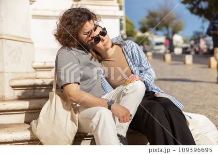 Romantic tourist couple is hugging while sitting outside on old city street and looking at side 109396695