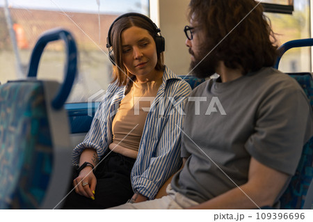 Young lovely tourist couple looking each other while riding in public bus Young lovely tourist couple looking each other while riding in public bus 109396696