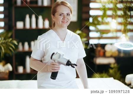happy female massage therapist in spa salon with massage pistol 109397128