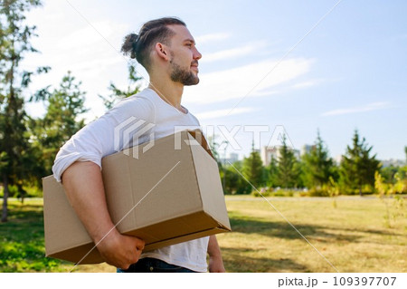 Man in white blazer holding cardboard boxes outdoor in summer park Man in white blazer holding cardboard boxes outdoor in summer park 109397707