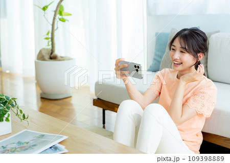 部屋でスマホを操作する若い女性 109398889