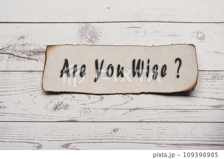 Text on burnt edge brown paper on wooden desk - Are you wise. Text on burnt edge brown paper on wooden desk - Are you wise. 109398985