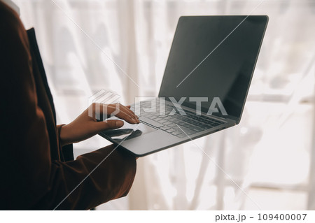 Attractive smiling young asian business woman work at home office, Asian woman working on laptop computer holding tablet. 109400007