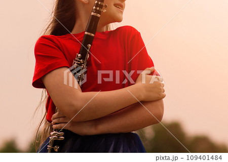 Young attractive girl playing clarinet, ebony in fall park Young attractive girl playing clarinet, ebony in fall park 109401484