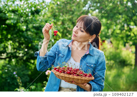 Happy woman with harvest of red ripe cherries in summer garden 109402127