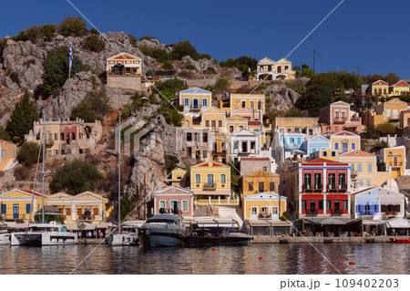 Multi-colored facades of houses in the village Symi on a sunny day. 109402203