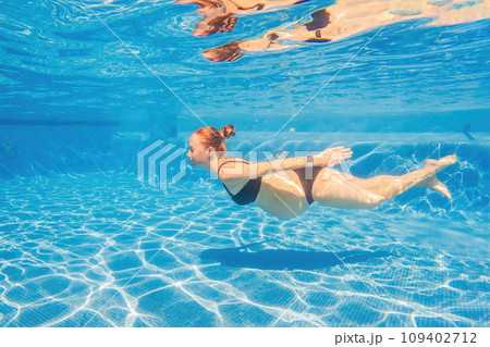 Pregnant serenity submerged a woman gracefully dives into the pool, celebrating the beauty of pregnancy with aquatic elegance 109402712