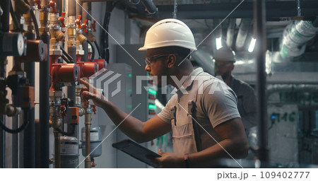 African American inspector checks pipeline system on factory 109402777