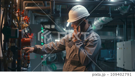 Heavy industry worker inspects pipeline system, talks by phone Heavy industry worker inspects pipeline system, talks by phone 109402791