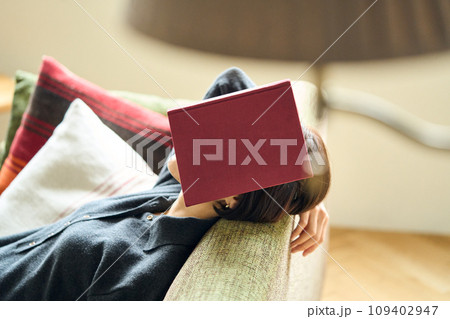 本を顔にのせて眠る女性 109402947