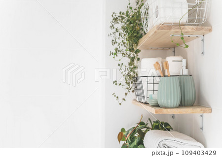 Beautiful white bathroom. Wooden shelves. Rolled towels, stacked towels and baskets. Beautiful white bathroom. Wooden shelves. Rolled towels, stacked towels and baskets. 109403429