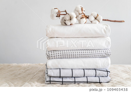 Cotton branch with pile of folded bed sheets and blankets 109403438