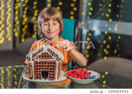 Immerse in festive delight as a boy crafts boy crafting an unconventional gingerbread house, infusing Christmas with unique creativity and festive cheer. A sweet scene of seasonal bonding and culinary Immerse in festive delight as a boy crafts boy crafting an unconventional gingerbread house, infusing Christmas with unique creativity and festive cheer. A sweet scene of seasonal bonding and culinary 109404591