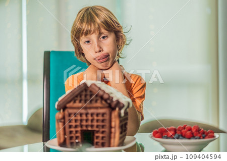Immerse in festive delight as a boy crafts boy crafting an unconventional gingerbread house, infusing Christmas with unique creativity and festive cheer. A sweet scene of seasonal bonding and culinary 109404594