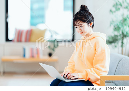 リビングでノートパソコンを操作するフリーランスの若い女性。 109404912