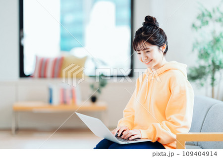 リビングでノートパソコンを操作するフリーランスの若い女性。 リビングでノートパソコンを操作するフリーランスの若い女性。 109404914