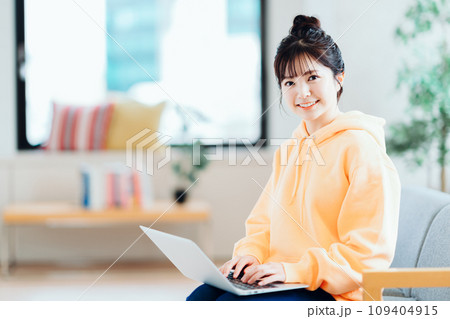 リビングでノートパソコンを操作するフリーランスの若い女性。 109404915
