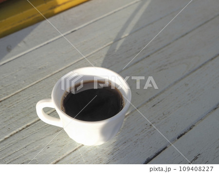 white cup of black coffee under morning sunshine on white wood table 109408227