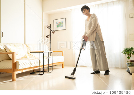 掃除機で床を掃除する女性 109409486