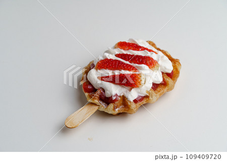 croissant waffles decorated with whipped cream, strawberries, nuts, banana and blueberries 109409720
