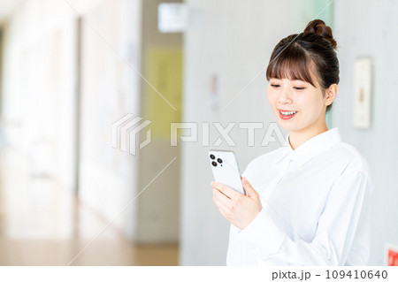スマホを操作する女子大生。撮影協力：有明教育芸術短期大学 109410640
