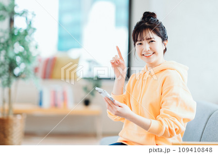 リビングでスマホを操作するフ若い女性。 109410848
