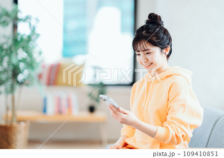 リビングでスマホを操作するフ若い女性。 リビングでスマホを操作するフ若い女性。 109410851