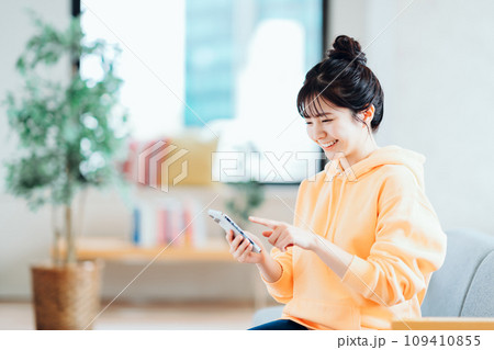 リビングでスマホを操作するフ若い女性。 リビングでスマホを操作するフ若い女性。 109410855