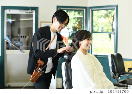 女性客のヘアスタイリングをする男性美容師 女性客のヘアスタイリングをする男性美容師 109411700