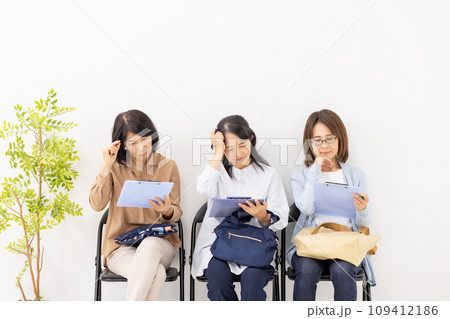 待合室でクリップボードに記入する女性　悩む 109412186