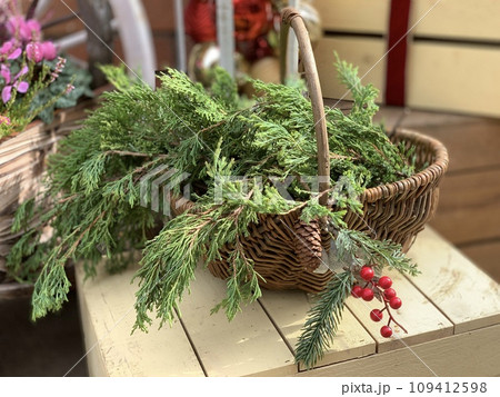 カゴに入ったクリスマスリースの手作り素材 針葉樹の枝と赤い実のナチュラルな冬のボタニカルイメージ カゴに入ったクリスマスリースの手作り素材 針葉樹の枝と赤い実のナチュラルな冬のボタニカルイメージ 109412598