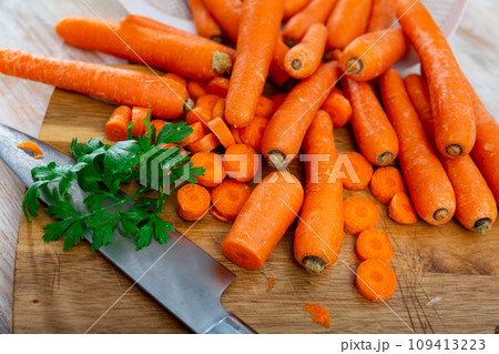 Pile of fresh sweet carrots on wooden cutting board Pile of fresh sweet carrots on wooden cutting board 109413223