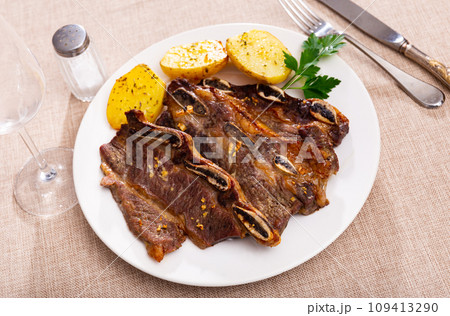 Grilled beef ribs churrasco with fried potatoes and greens 109413290