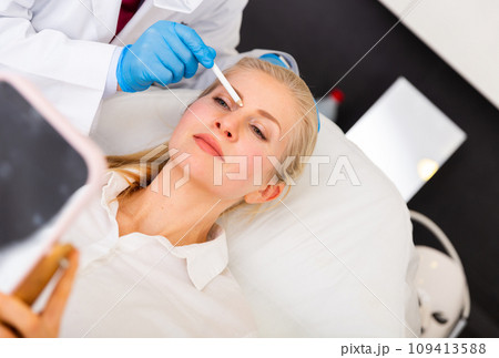 Young woman on doctor-cosmetologist's appointment Young woman on doctor-cosmetologist's appointment 109413588