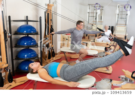 Girl is engaged in Pilates simulator with cable and ropes for stretching leg muscles 109413659