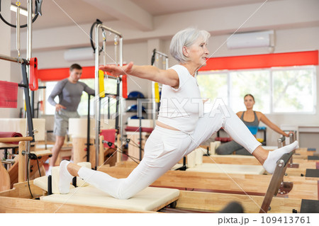 Elderly woman doing stretching on pilates machine 109413761