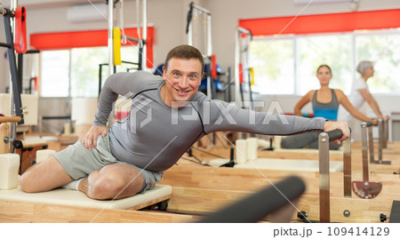 Adult man doing stretching on pilates machine Adult man doing stretching on pilates machine 109414129