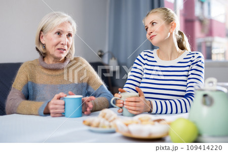 Mature mother and her adult daughter drink tea and chat 109414220