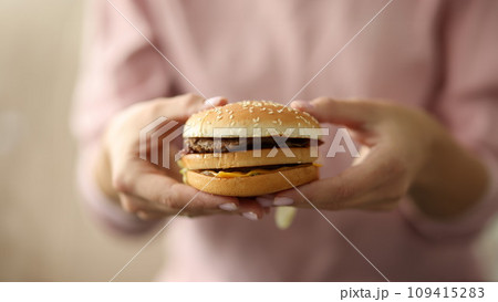 Female hands hold hamburger close-up 109415283