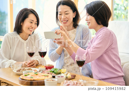 スマートフォンでパーティーの様子を撮影する女性 109415982