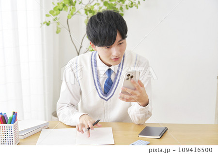 自宅でスマートフォンを使って勉強する男子高校生 109416500