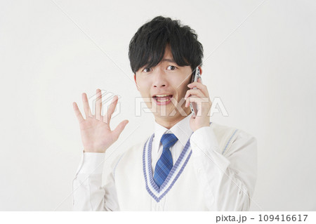 スマートフォンで電話をしながら驚く男子高校生　白背景 109416617