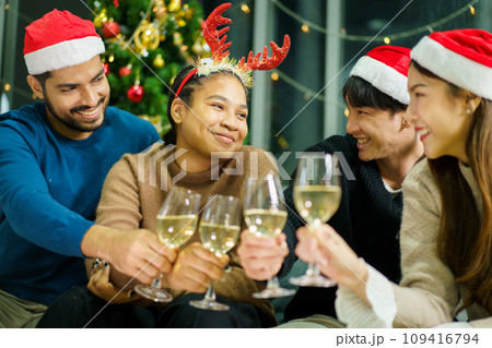 Group of diverse ethnicity young people enjoy celebrating a Christmas and New Year party together with a lot of foods and drinks. Friends celebrate Christmas and New Year festival and drink a wine. Group of diverse ethnicity young people enjoy celebrating a Christmas and New Year party together with a lot of foods and drinks. Friends celebrate Christmas and New Year festival and drink a wine. 109416794