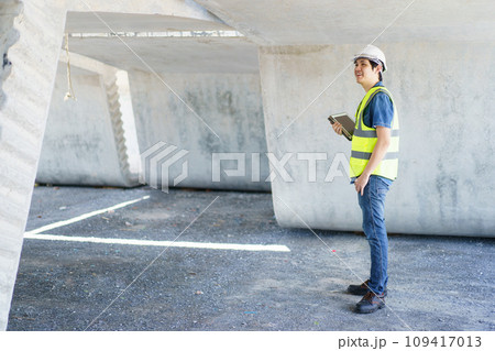 Asian professional - senior cilvil or construction engineer inspecting a segmenting bridge blueprint and construction plan at the site, civil engineer working at bridge construction site. Asian professional - senior cilvil or construction engineer inspecting a segmenting bridge blueprint and construction plan at the site, civil engineer working at bridge construction site. 109417013